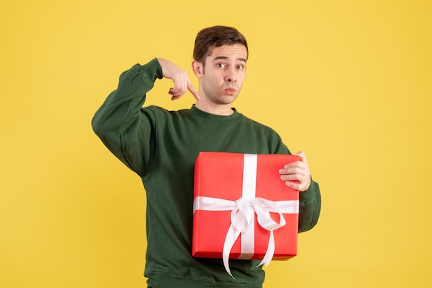 Vue de face jeune homme avec pull vert debout sur jaune