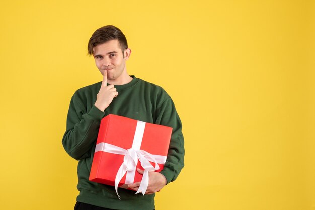 Vue de face jeune homme avec pull vert debout sur jaune