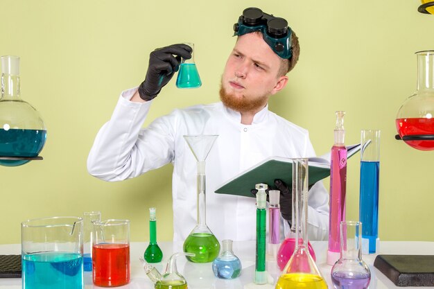 Vue de face jeune homme regardant un produit chimique bleu clair