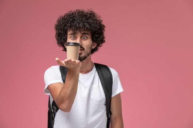 Vue de face jeune homme regardant sa tasse de café en papier