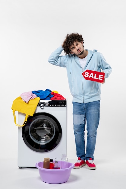 Photo gratuite vue de face d'un jeune homme avec une rondelle tenant une bannière de vente rouge sur un mur blanc