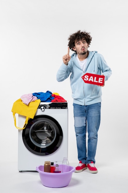 Vue de face d'un jeune homme avec une rondelle tenant une bannière de vente rouge sur un mur blanc