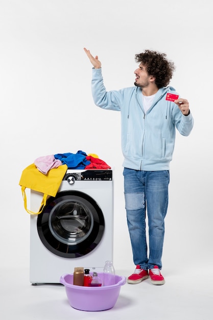 Vue De Face D'un Jeune Homme Avec Une Rondelle Tenant Une Carte Bancaire Rouge Sur Un Mur Blanc