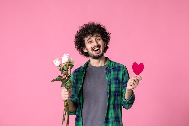 Vue de face jeune homme avec roses roses et autocollant coeur rose