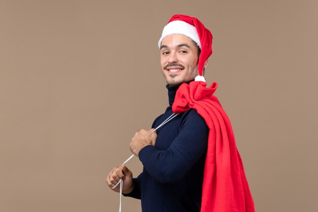 Vue de face jeune homme avec sac cadeau rouge, émotion de vacances de Noël