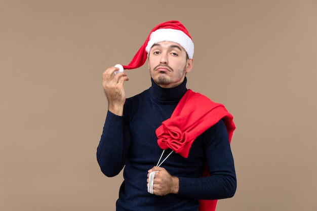 Vue de face jeune homme avec sac et casquette présents, vacances noël santa