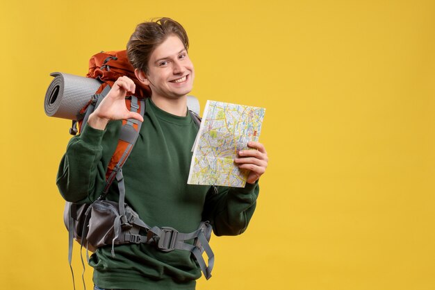 Vue de face jeune homme avec sac à dos tenant la carte