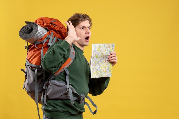 Vue de face jeune homme avec sac à dos tenant la carte