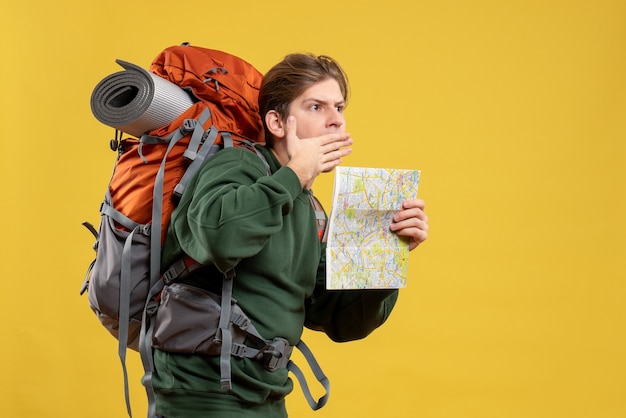 Vue de face jeune homme avec sac à dos tenant la carte