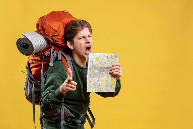 Vue de face jeune homme avec sac à dos tenant la carte