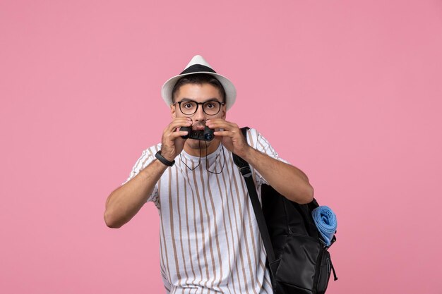 Vue de face jeune homme avec sac et jumelles sur un bureau rose