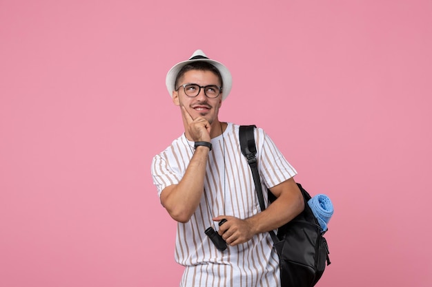 Vue de face jeune homme avec sac et jumelles sur fond rose