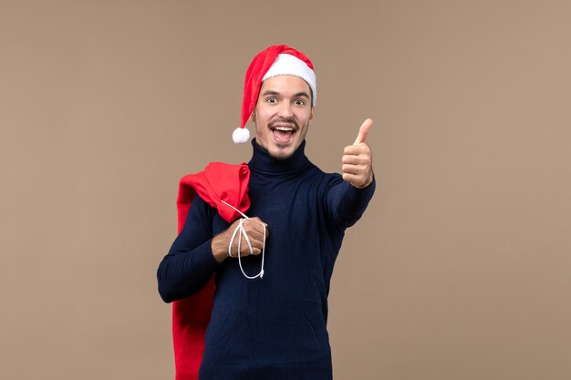 Vue de face jeune homme avec sac présent sur un bureau marron santa vacances noël