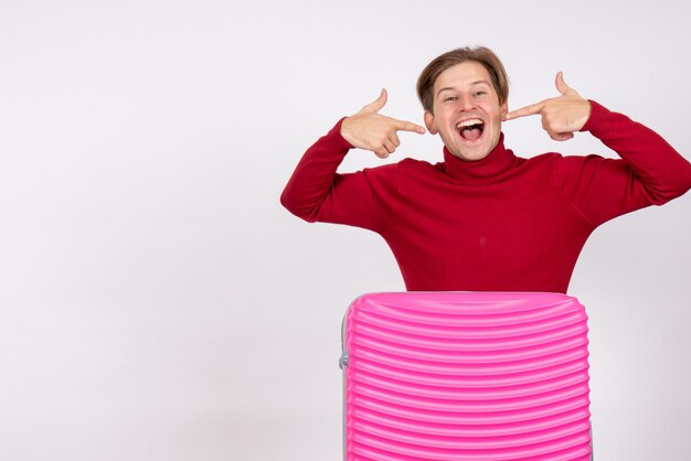 Vue de face jeune homme avec sac rose se réjouissant sur fond blanc