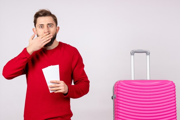 Vue de face jeune homme avec sac rose et tenant des billets sur un mur blanc voyage couleur vacances vol voyage été