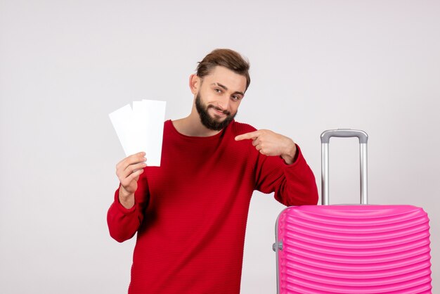 Vue de face jeune homme avec sac rose et tenant des billets sur un mur blanc voyage vol couleur voyage vacances photo