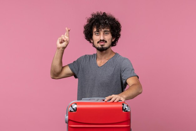 Vue de face jeune homme avec sac rouge sur un espace rose clair