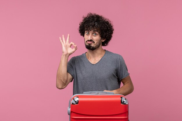 Vue de face jeune homme avec sac rouge posant sur l'espace rose