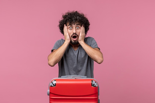 Vue de face jeune homme avec sac rouge se préparant pour un voyage sur l'espace rose