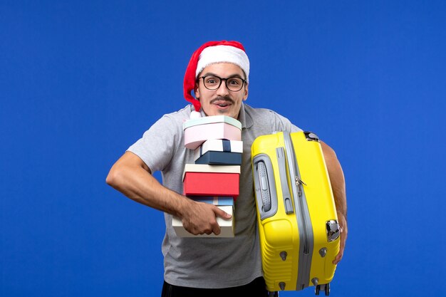 Vue De Face Jeune Homme Sac De Transport Et Présente Sur L'avion De Vacances De Vols De Mur Bleu