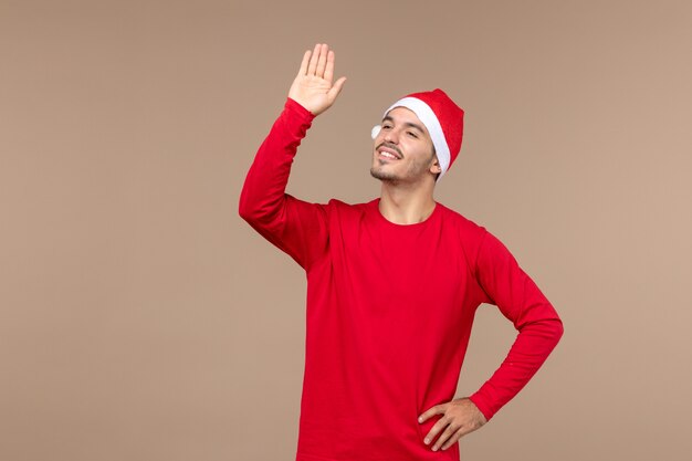 Vue de face jeune homme salutation et agitant sur fond brun émotion de vacances de Noël