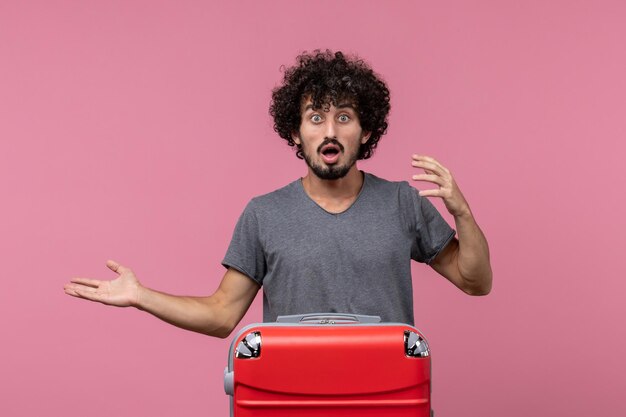 Vue de face jeune homme se préparant pour des vacances sur un espace rose