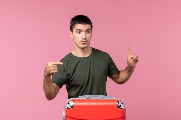 Vue de face jeune homme se préparant pour des vacances avec un grand sac sur l'espace rose