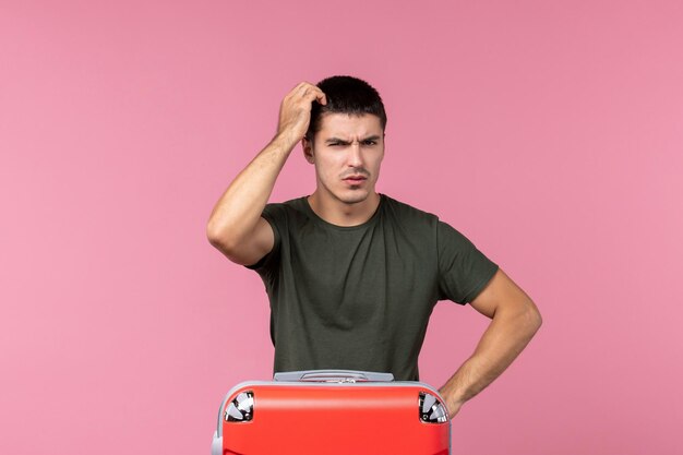 Vue de face jeune homme se préparant pour les vacances et pensant à l'espace rose