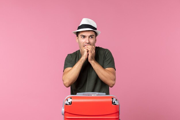 Vue de face jeune homme se préparant pour des vacances portant un chapeau sur un espace rose