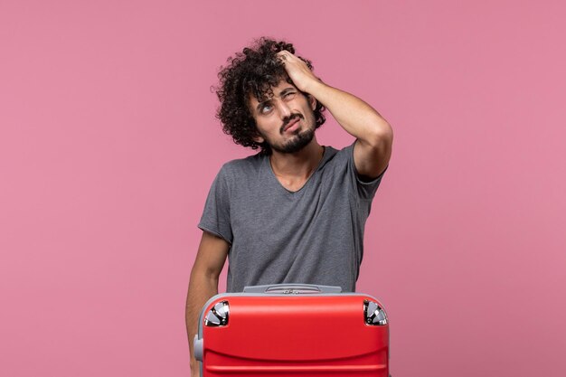 Vue de face jeune homme se préparant pour les vacances et réfléchissant à l'espace rose