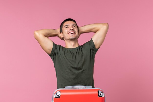 Vue de face jeune homme se préparant pour les vacances et se sentant heureux sur l'espace rose