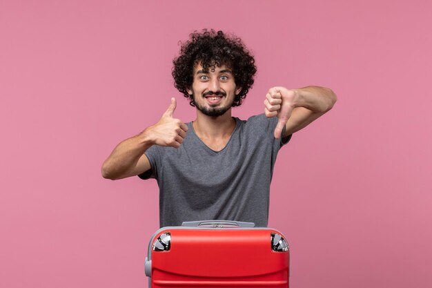 Vue de face jeune homme se préparant pour des vacances souriant sur un espace rose