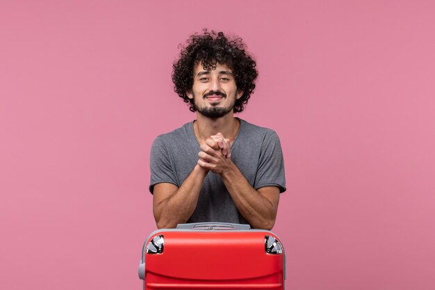 Vue de face jeune homme se préparant pour des vacances souriant sur un espace rose