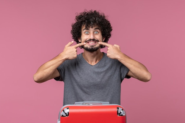 Photo gratuite vue de face jeune homme se préparant pour un voyage avec un sac sur l'espace rose