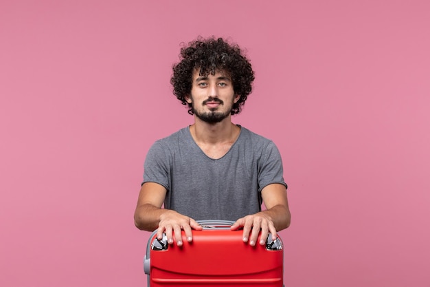 Vue de face jeune homme se préparant pour un voyage avec un sac sur l'espace rose