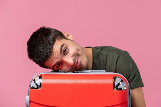 Vue de face jeune homme se préparant pour le voyage et se sentant fatigué sur l'espace rose