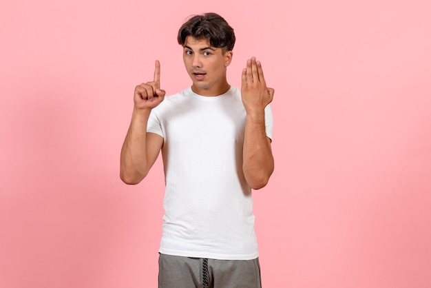 Vue de face jeune homme en t-shirt blanc sur un bureau rose