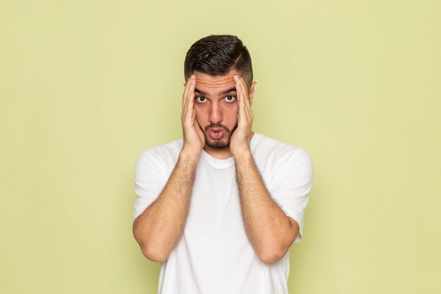 Une vue de face jeune homme en t-shirt blanc avec expression confuse