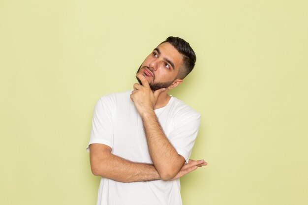 Une vue de face jeune homme en t-shirt blanc avec expression de pensée