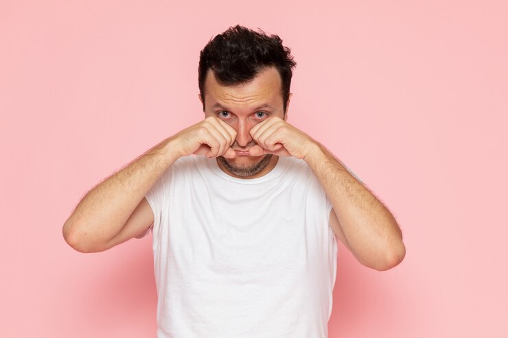 Photo gratuit une vue de face jeune homme en t-shirt blanc faux pleurer sur le bureau rose homme couleur émotion pose