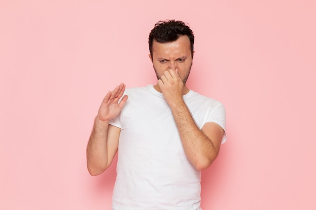 Une vue de face jeune homme en t-shirt blanc fermant son nez