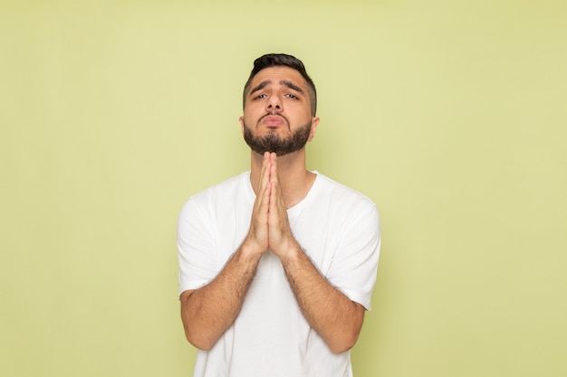 Une vue de face jeune homme en t-shirt blanc mendicité