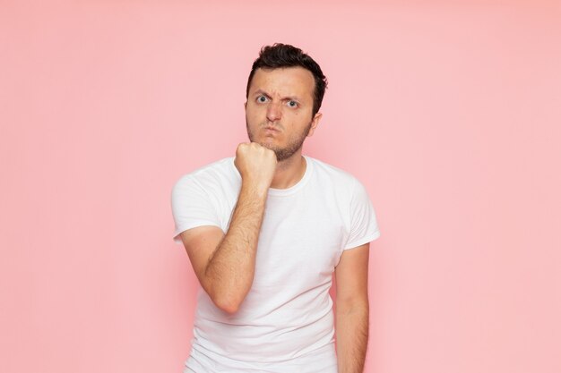 Une vue de face jeune homme en t-shirt blanc posant avec une expression agressive