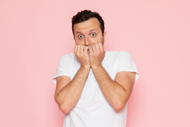 Une vue de face jeune homme en t-shirt blanc posant avec expression effrayée