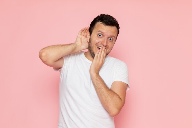 Une vue de face jeune homme en t-shirt blanc posant avec une expression excitée