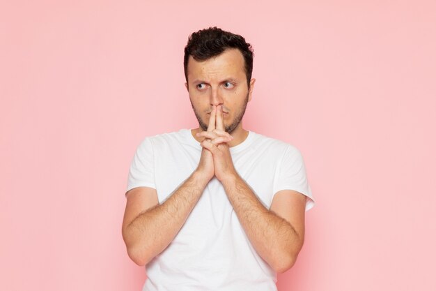 Une vue de face jeune homme en t-shirt blanc posant avec expression de pensée