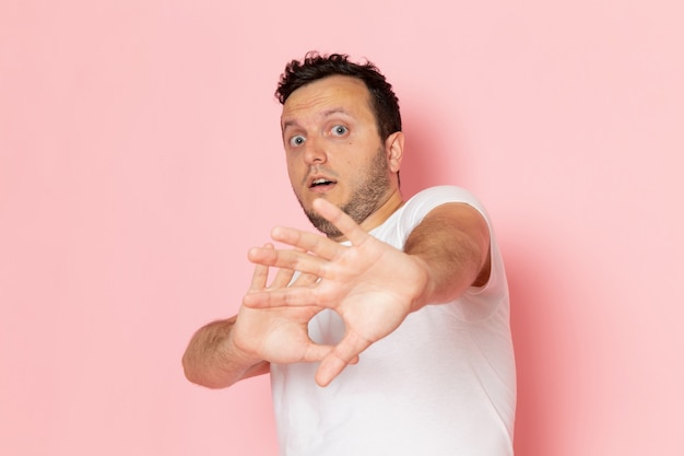 Une vue de face jeune homme en t-shirt blanc posant avec une expression prudente