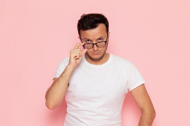 Une vue de face jeune homme en t-shirt blanc posant avec des lunettes de soleil optiques