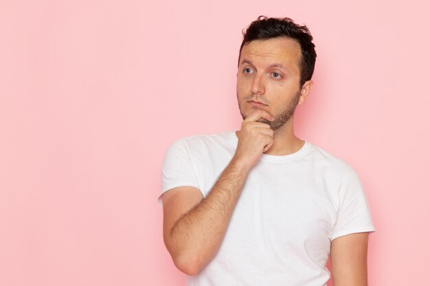 Une vue de face jeune homme en t-shirt blanc posant et pensant