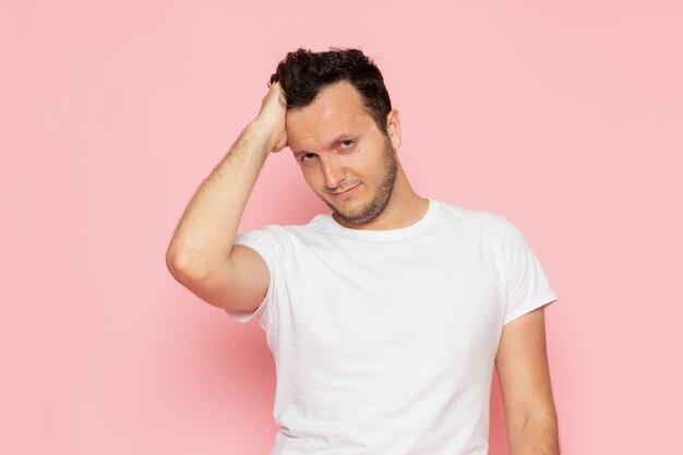 Une vue de face jeune homme en t-shirt blanc posant